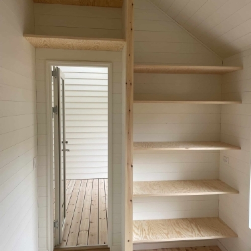 Renovering af rum med indbyggede hylder, trægulv og udgang til terrasse