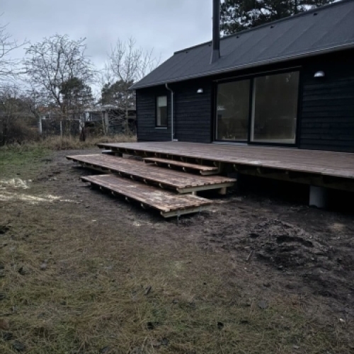 Træterrasse opbygning med trappetrin foran hus med mørk facade