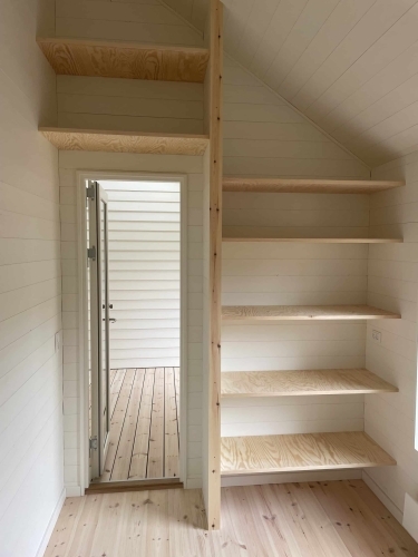 Renovering af rum med indbyggede hylder, trægulv og udgang til terrasse